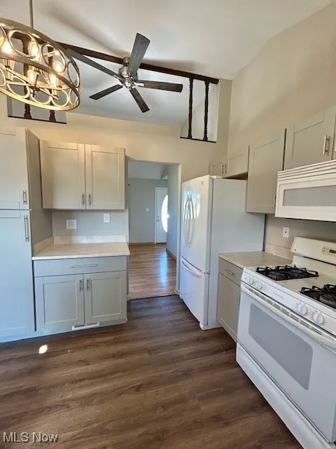 Kitchen with white appliances, dark wood-type flooring, a chandelier, and light countertops