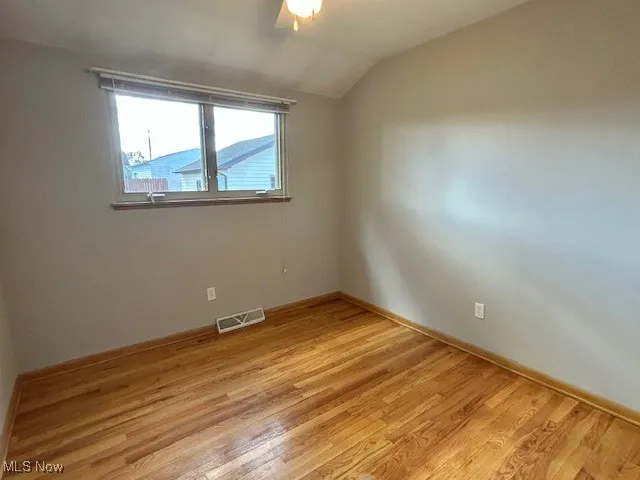 Spare room with lofted ceiling and light wood-style floors