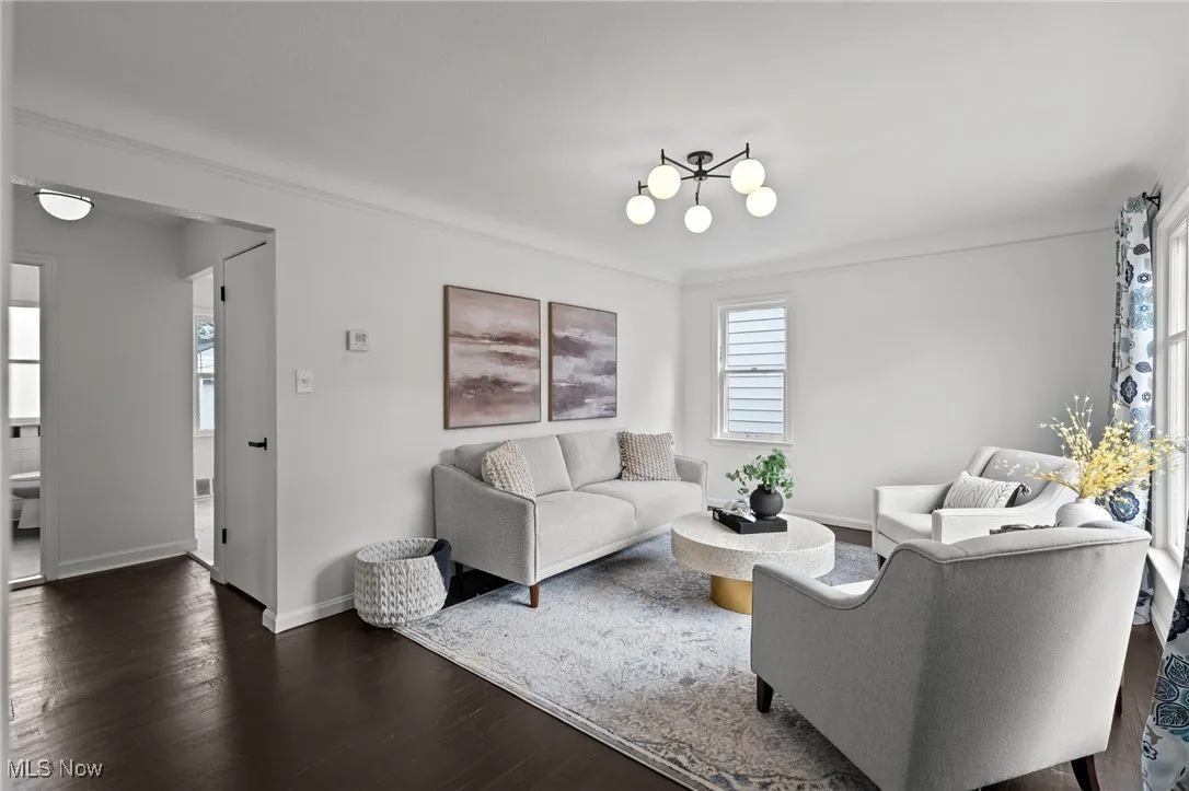 Living room featuring wood finished floors, a chandelier, and ornamental molding