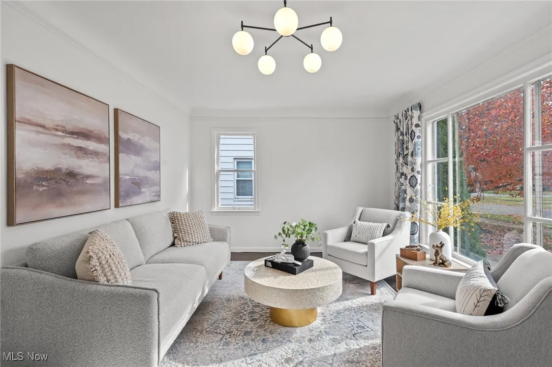 Living area with ornamental molding, wood finished floors, and a chandelier