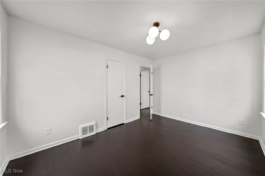Empty room with dark wood-style flooring and baseboards