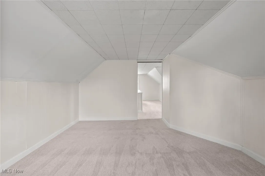 Additional living space with light carpet and lofted ceiling