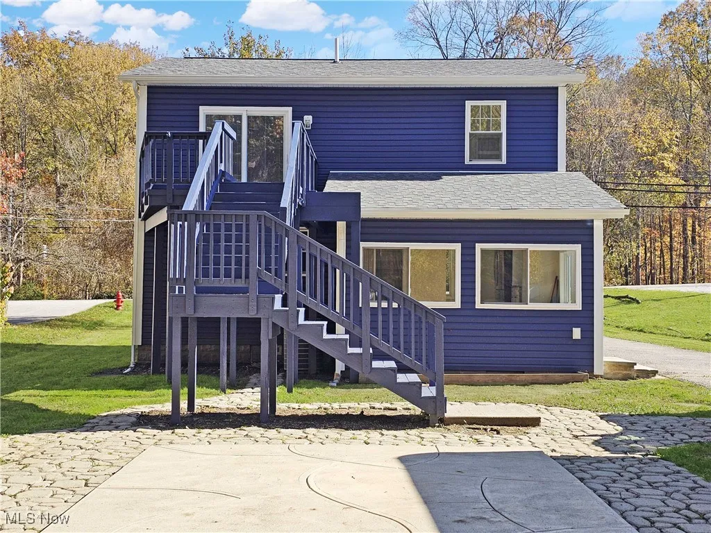 Back of house with stairway, a yard, a shingled roof, and a patio