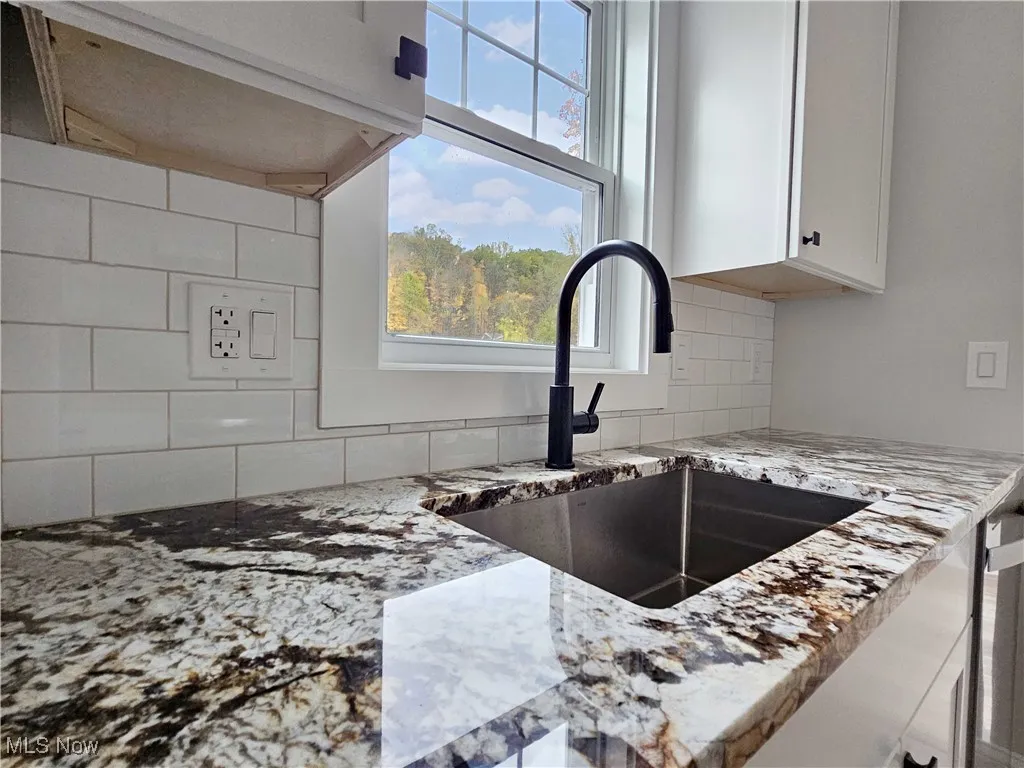Kitchen with light stone counters and white cabinetry