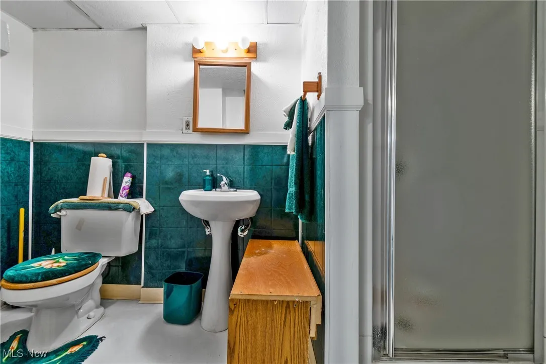 Full bathroom with a shower stall, tile walls, and wainscoting