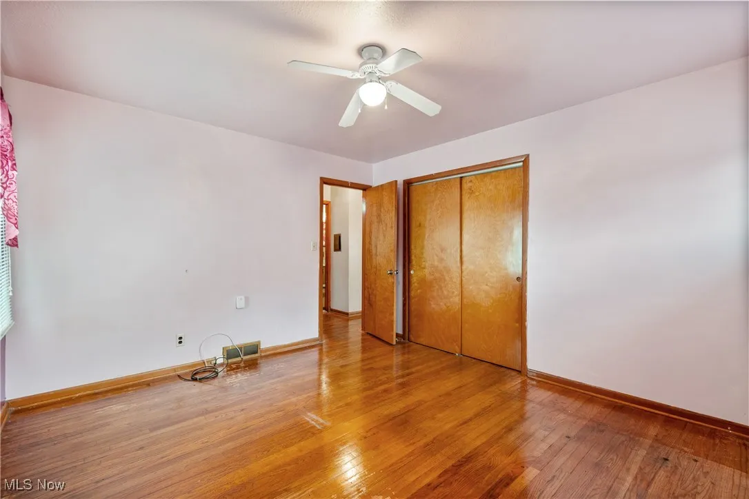 Unfurnished bedroom featuring wood-type flooring, a closet, and a ceiling fan