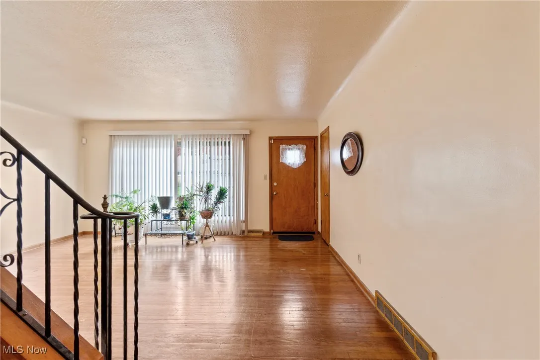 Foyer entrance with wood-type flooring, a textured ceiling, and stairway
