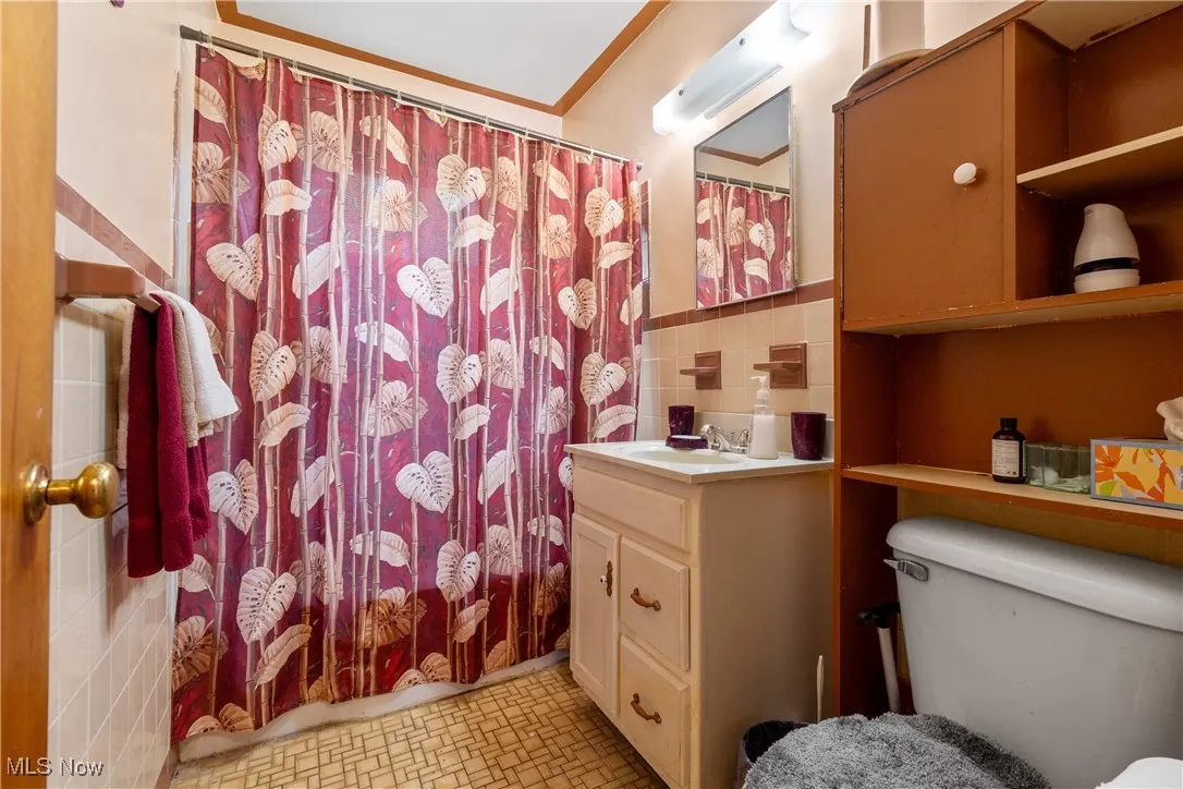 Full bathroom with tile walls, vanity, backsplash, and shower / bath combo