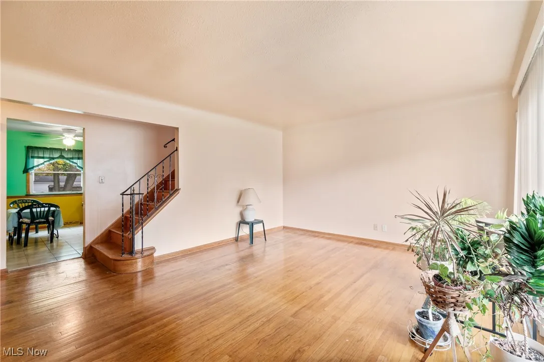 Unfurnished living room with wood finished floors, stairs, and ceiling fan
