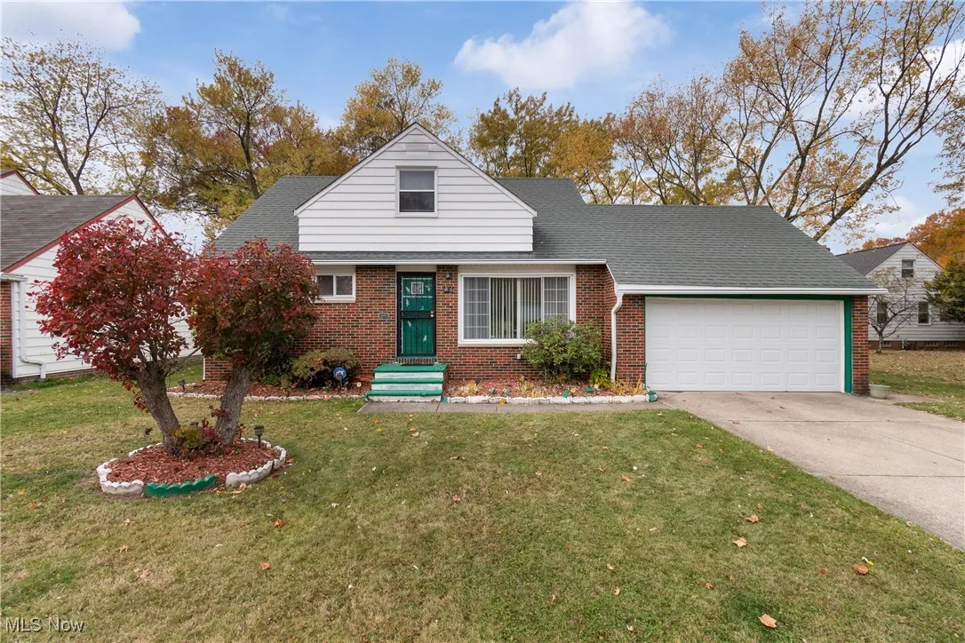 View of front of home featuring a front lawn, driveway, brick siding, and an attached garage