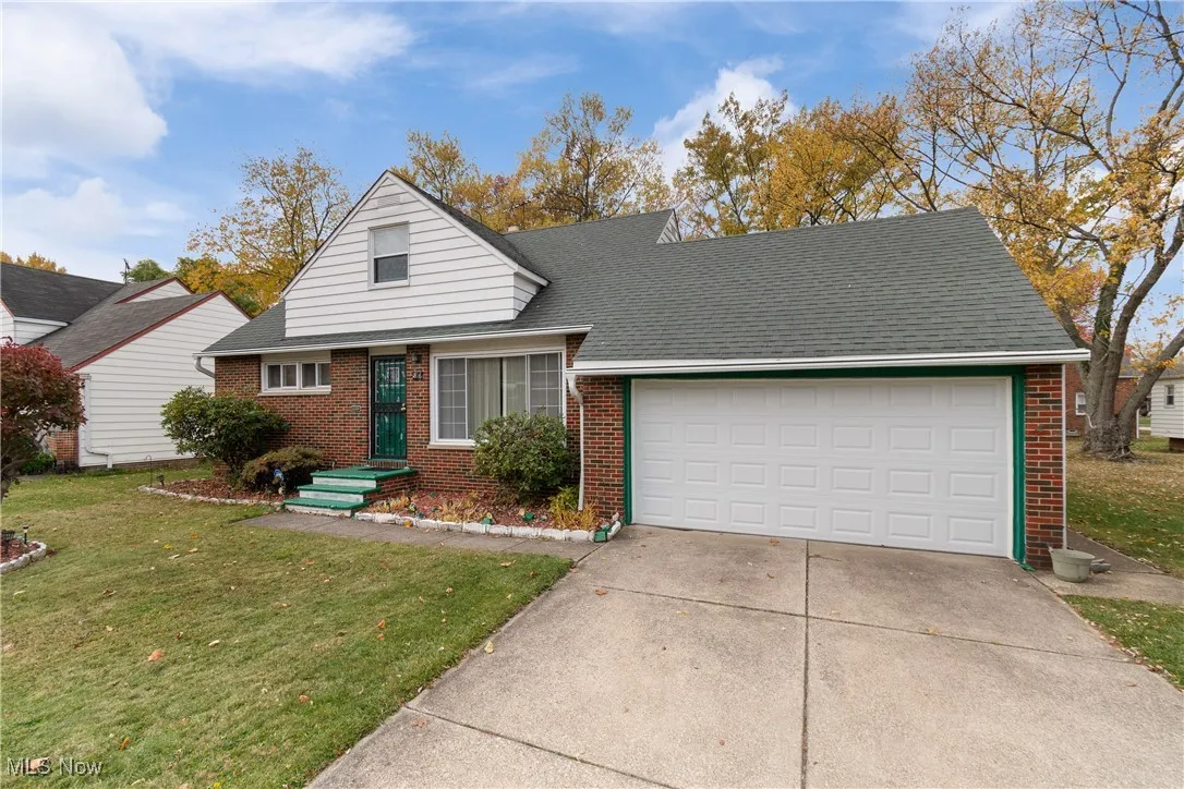 View of front of property with a front yard, brick siding, a garage, and driveway