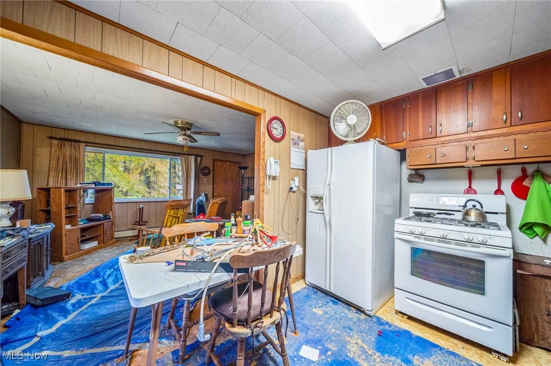 Kitchen with wood panel walls, brown cabinets and appliances