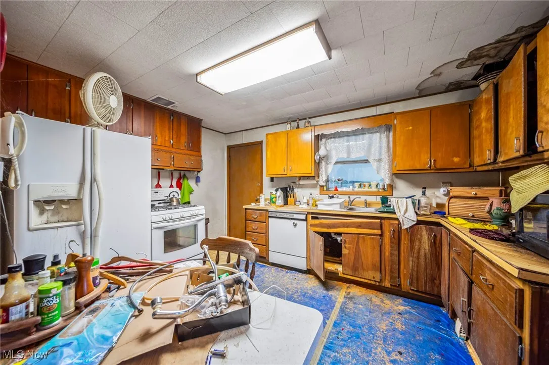 Kitchen with wood panel walls, brown cabinets and appliances. Doorway to back screened in porch
