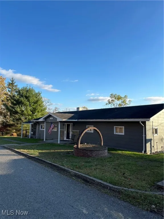 Ranch-style house featuring a front lawn, a chimney, and covered porch