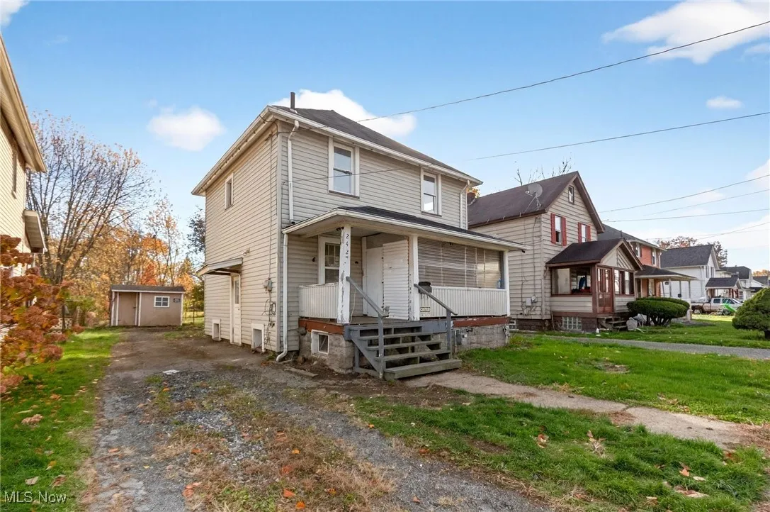 American foursquare style home with an outbuilding, driveway, and a front lawn