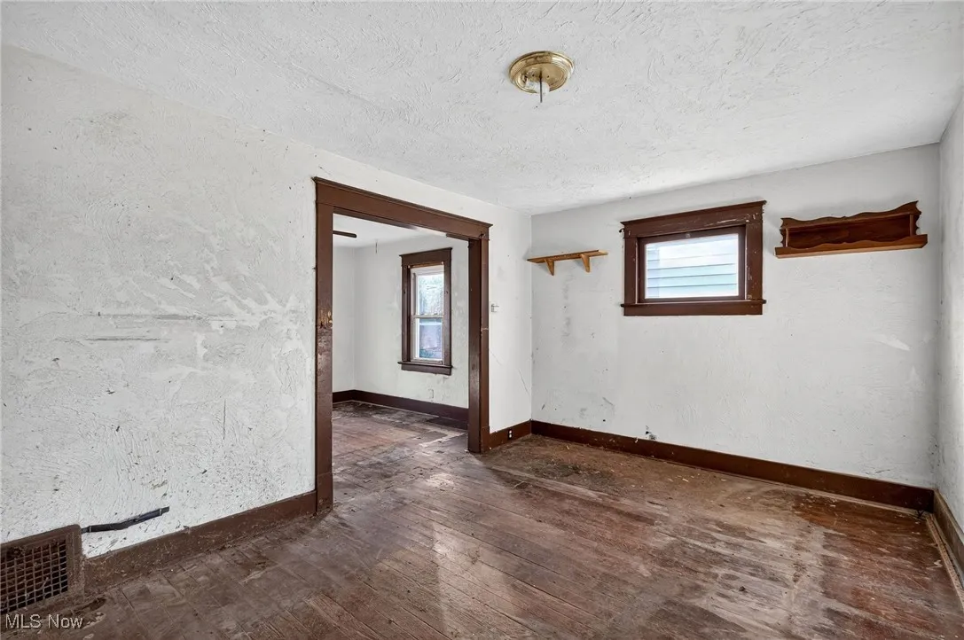Unfurnished room featuring dark wood-style floors, a textured wall, and a textured ceiling