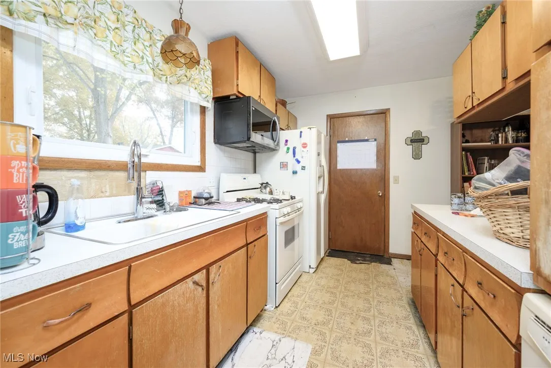 Kitchen with white appliances, brown cabinets, light countertops, and light flooring