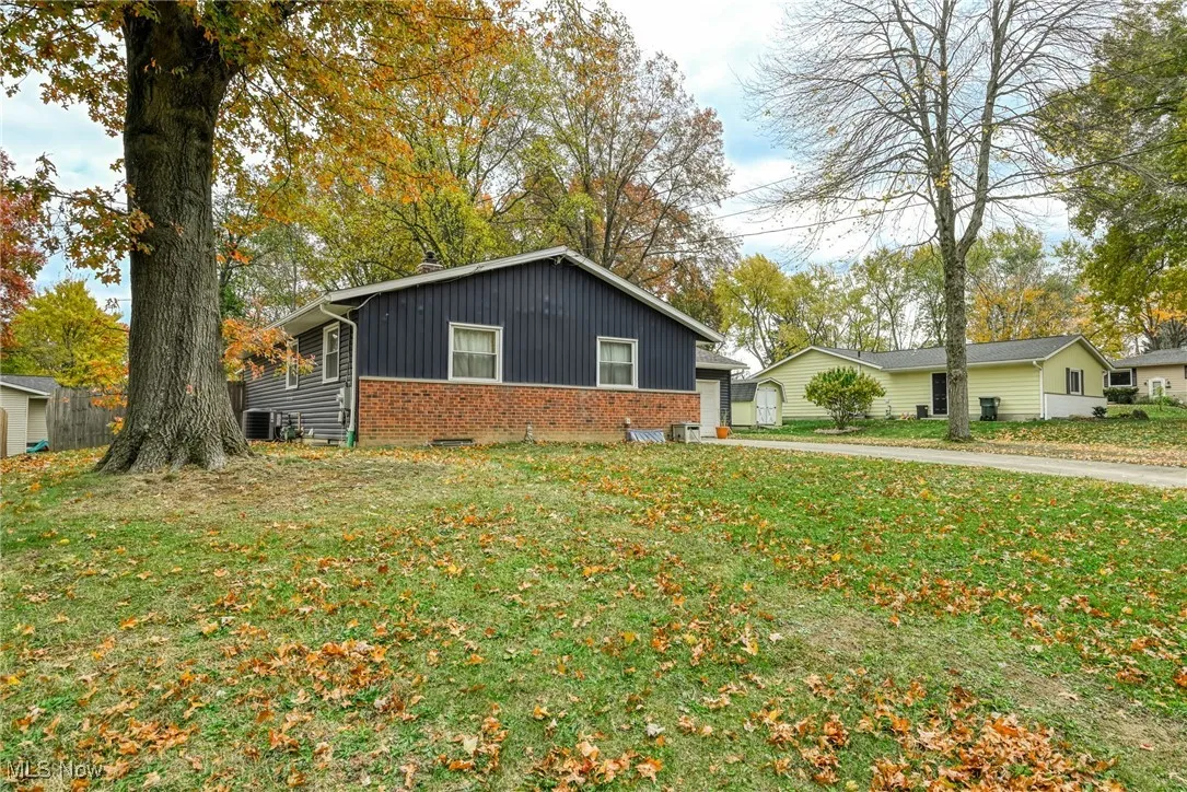 View of front of home with brick siding, a front yard, board and batten siding, and a garage
