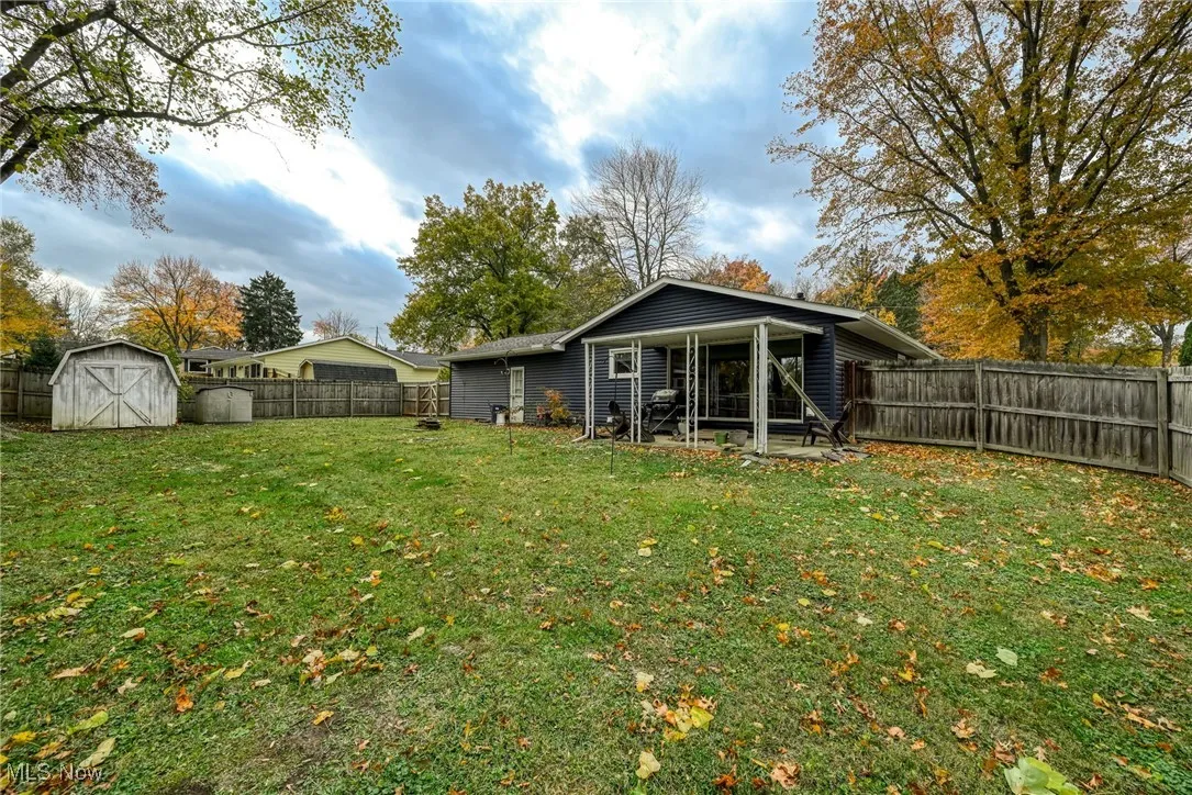 Back of house with a fenced backyard, a patio area, and a storage shed