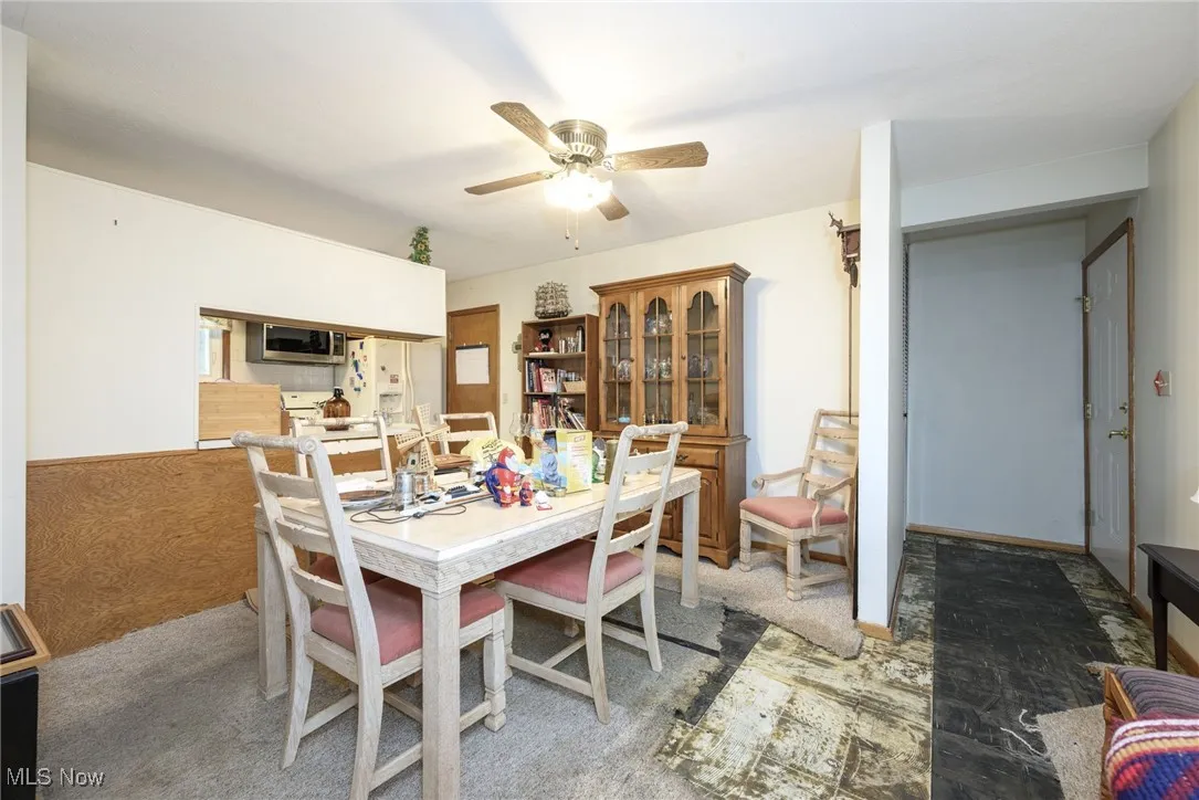 Dining room featuring a ceiling fan and light colored carpet