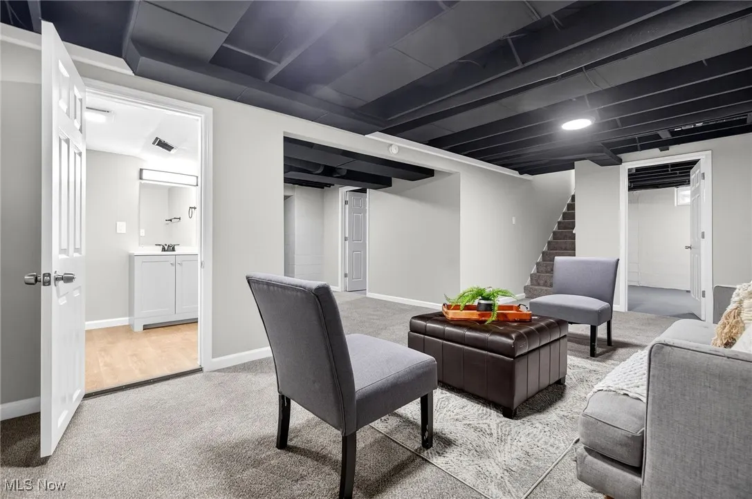 Carpeted living area with baseboards and stairs