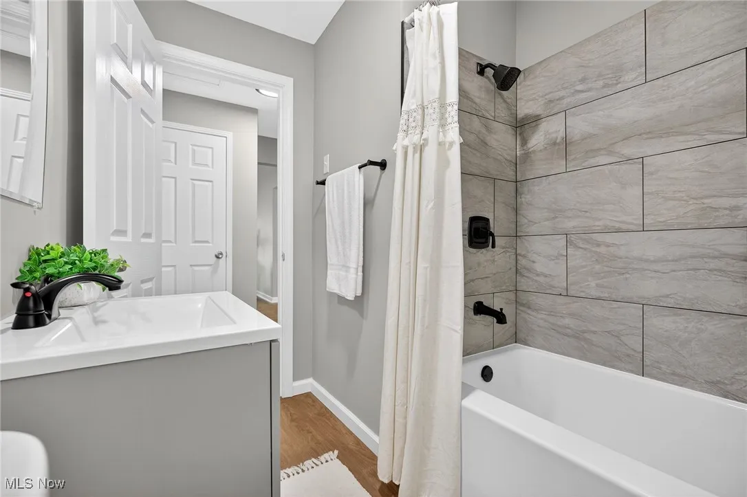 Bathroom with shower / bath combo with shower curtain, vanity, and wood finished floors