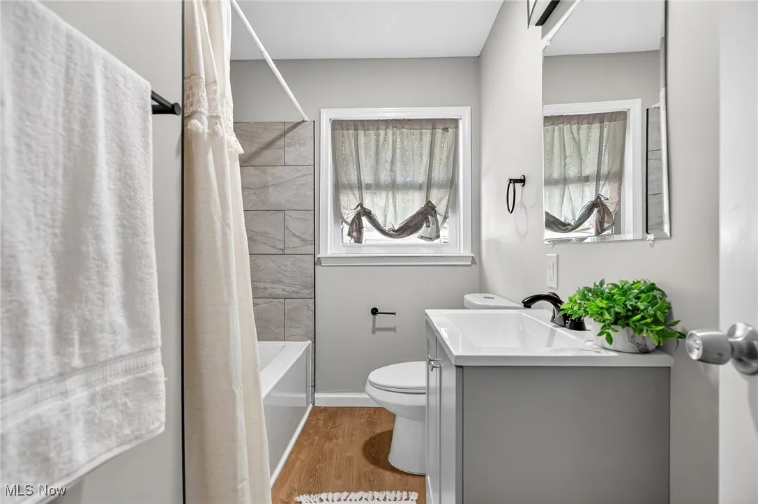 Bathroom with vanity, light wood-style flooring, and shower / bathtub combination with curtain