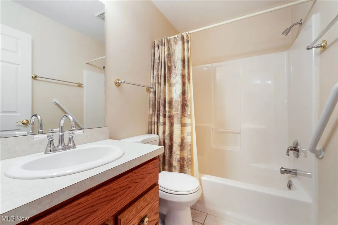 Bathroom with vanity, light tile patterned floors, and shower / bathtub combination with curtain