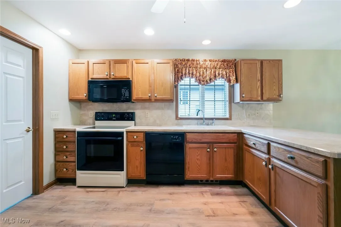 Kitchen with black appliances, decorative backsplash, light wood finished floors, recessed lighting, and brown cabinetry