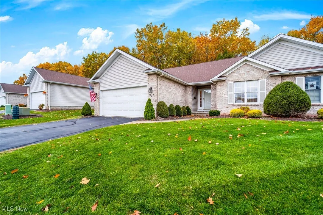 View of front of home featuring a front yard, brick siding, an attached garage, asphalt driveway, and a shingled roof