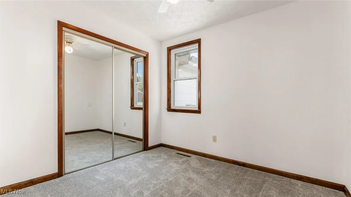 Unfurnished bedroom with a textured ceiling, a closet, carpet, and ceiling fan