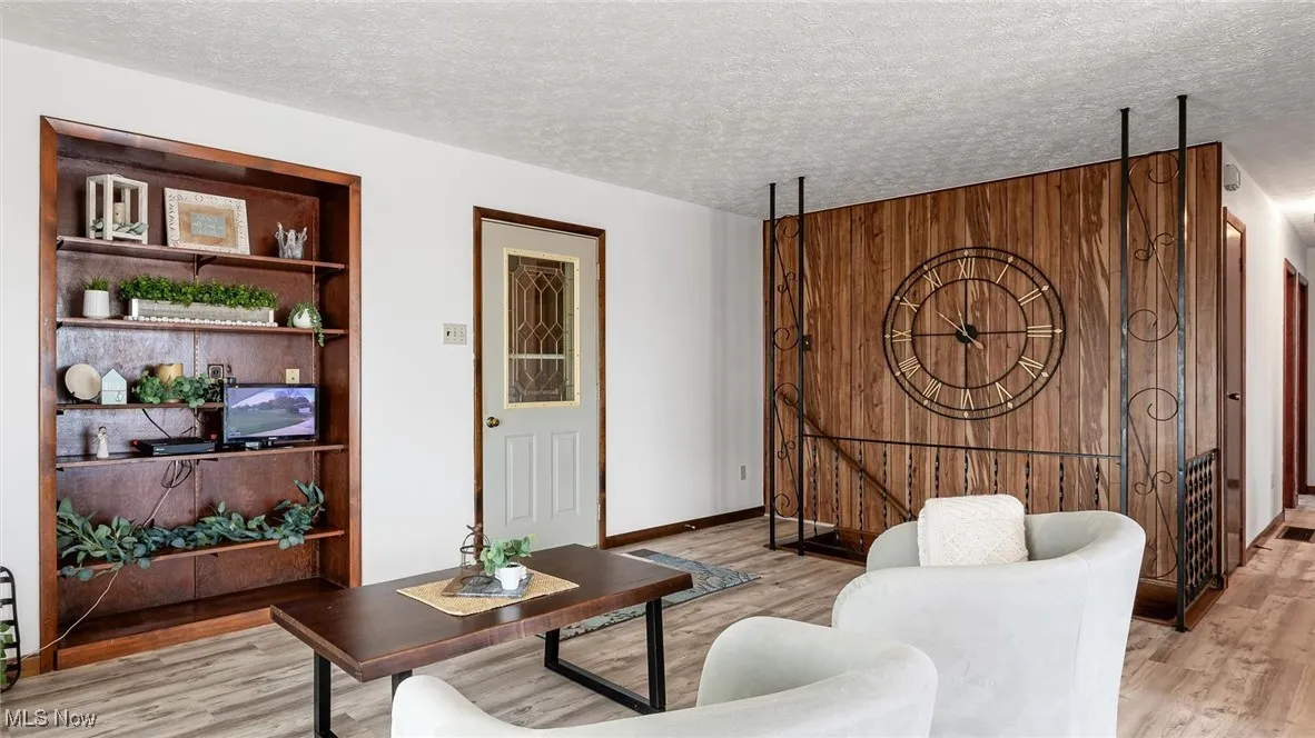 Living room with light wood finished floors, a textured ceiling, and built in shelves