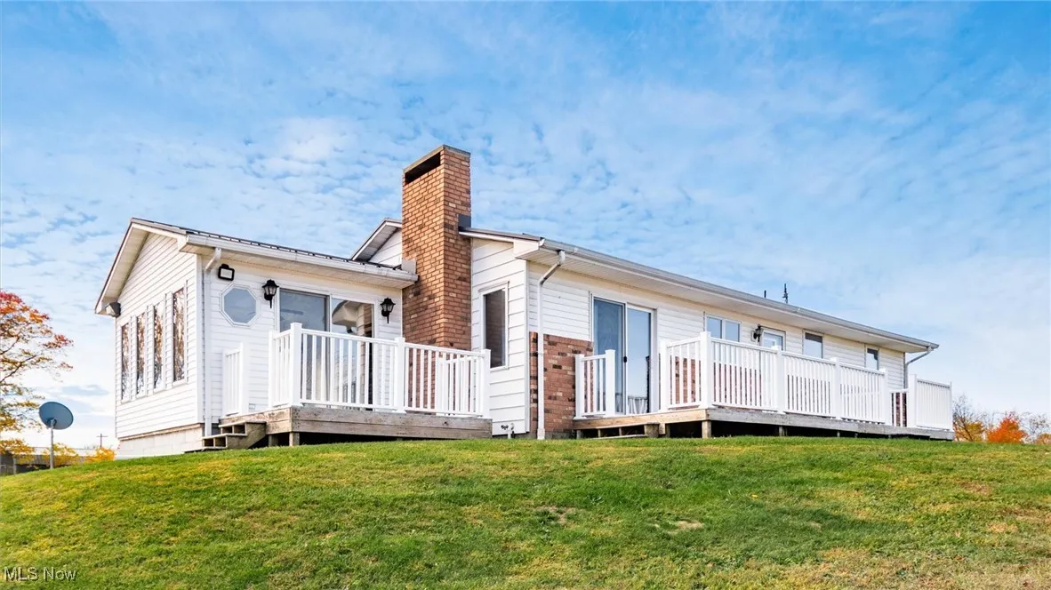 Rear view of house with a yard, a deck, and a chimney