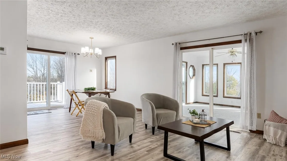 Living room with a textured ceiling, light wood-type flooring, and healthy amount of natural light