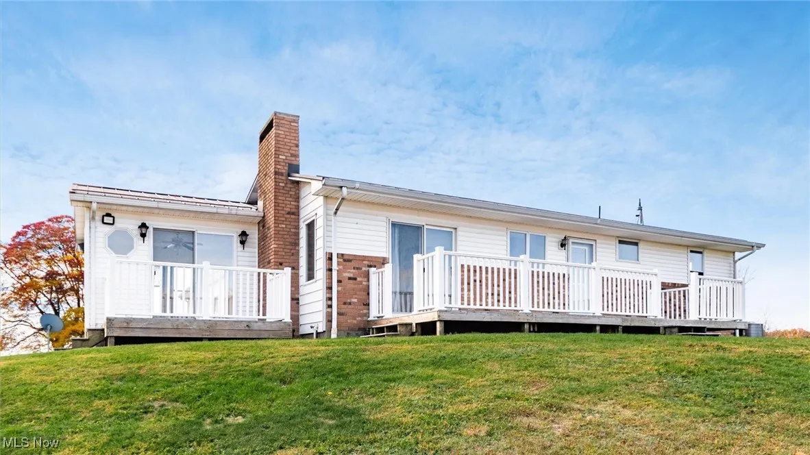 Rear view of house featuring a wooden deck, a yard, and a chimney
