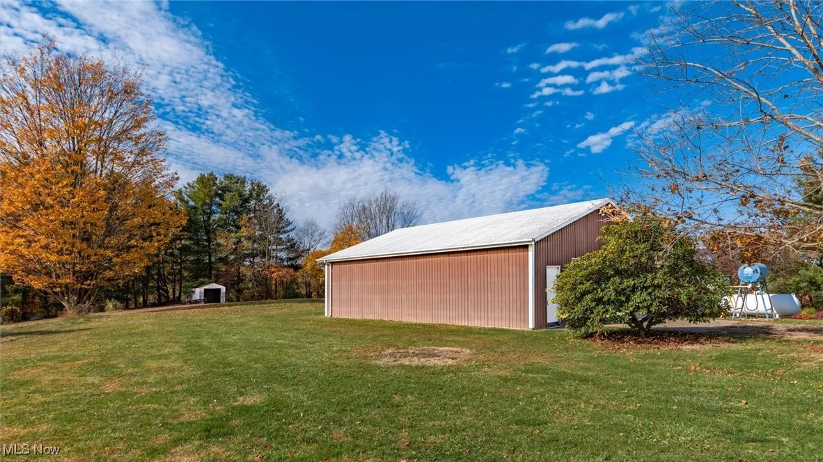 View of grassy yard with an outdoor structure and a pole building