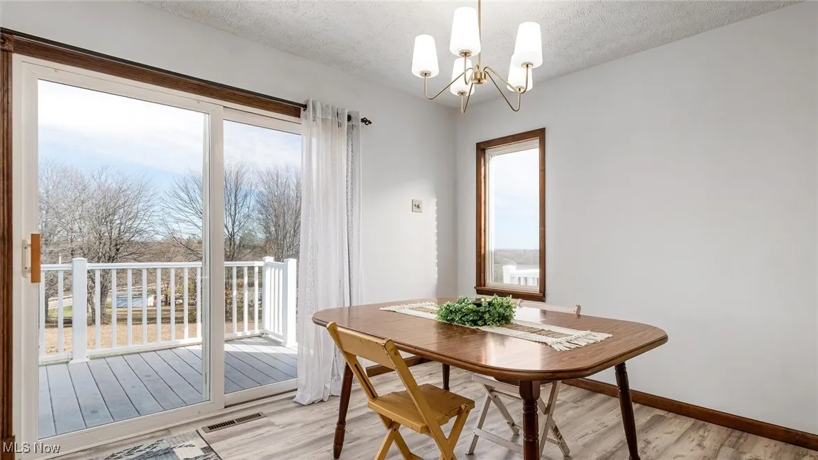 Dining space featuring light wood-type flooring, a textured ceiling, and a chandelier