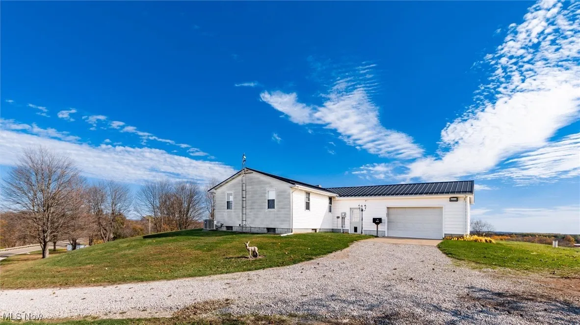 View of property exterior featuring a metal roof, driveway, a yard, and a garage