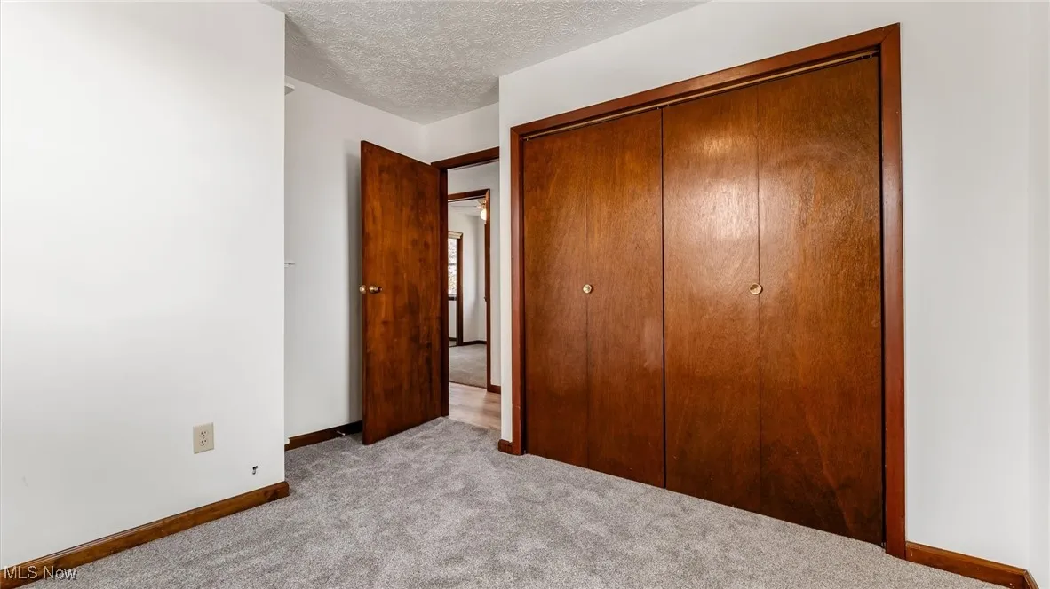 Unfurnished bedroom featuring a closet, a textured ceiling, and carpet floors
