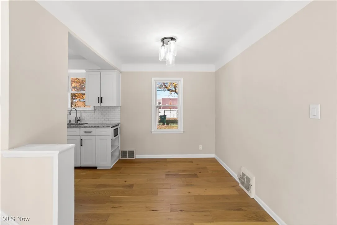 Unfurnished dining area featuring light wood-style flooring and baseboards