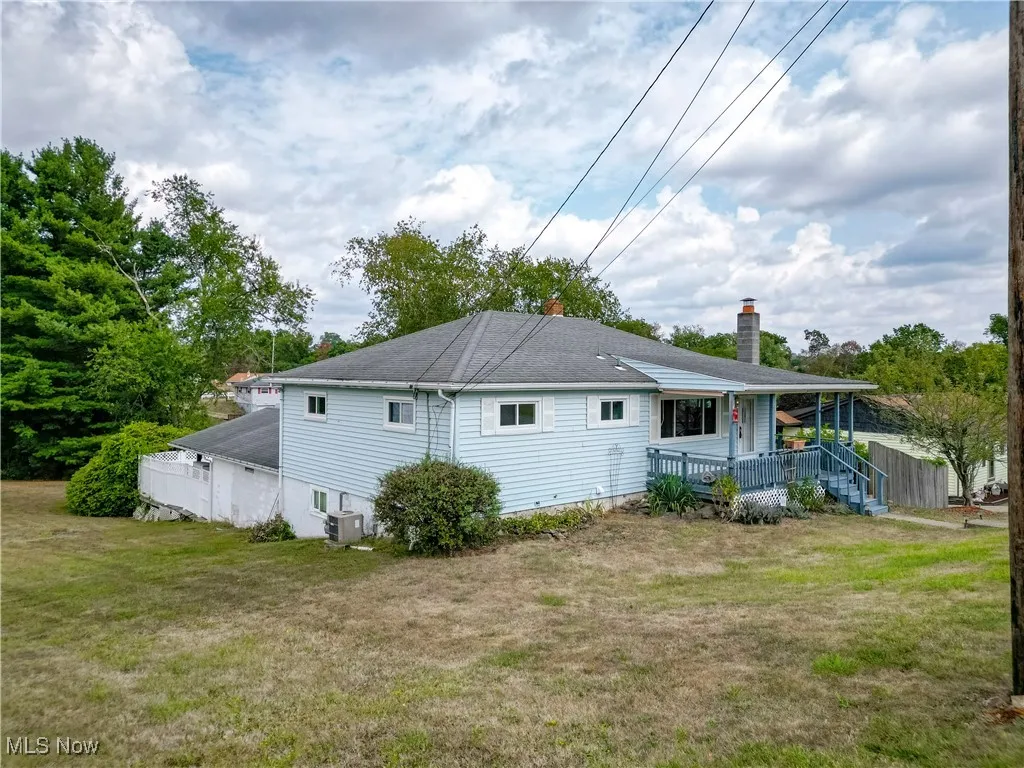Back of property featuring a yard, a chimney, and covered porch