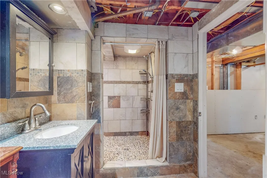 Full bathroom featuring vanity, a stall shower, and tile walls