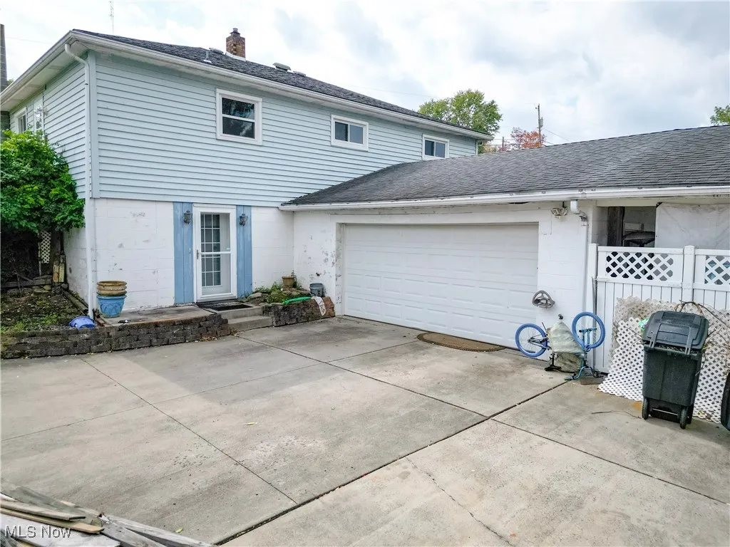 View of front facade featuring concrete driveway, roof with shingles, a chimney, and an attached garage