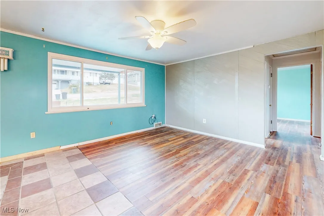 Spare room featuring a ceiling fan, ornamental molding, and light wood-style floors