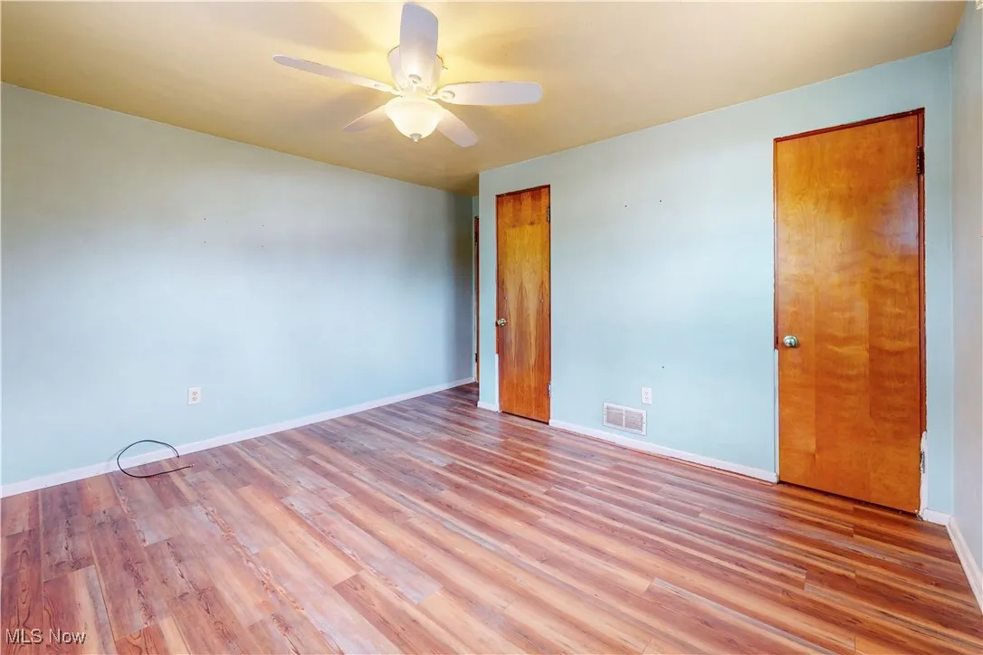 Unfurnished bedroom with ceiling fan and wood finished floors