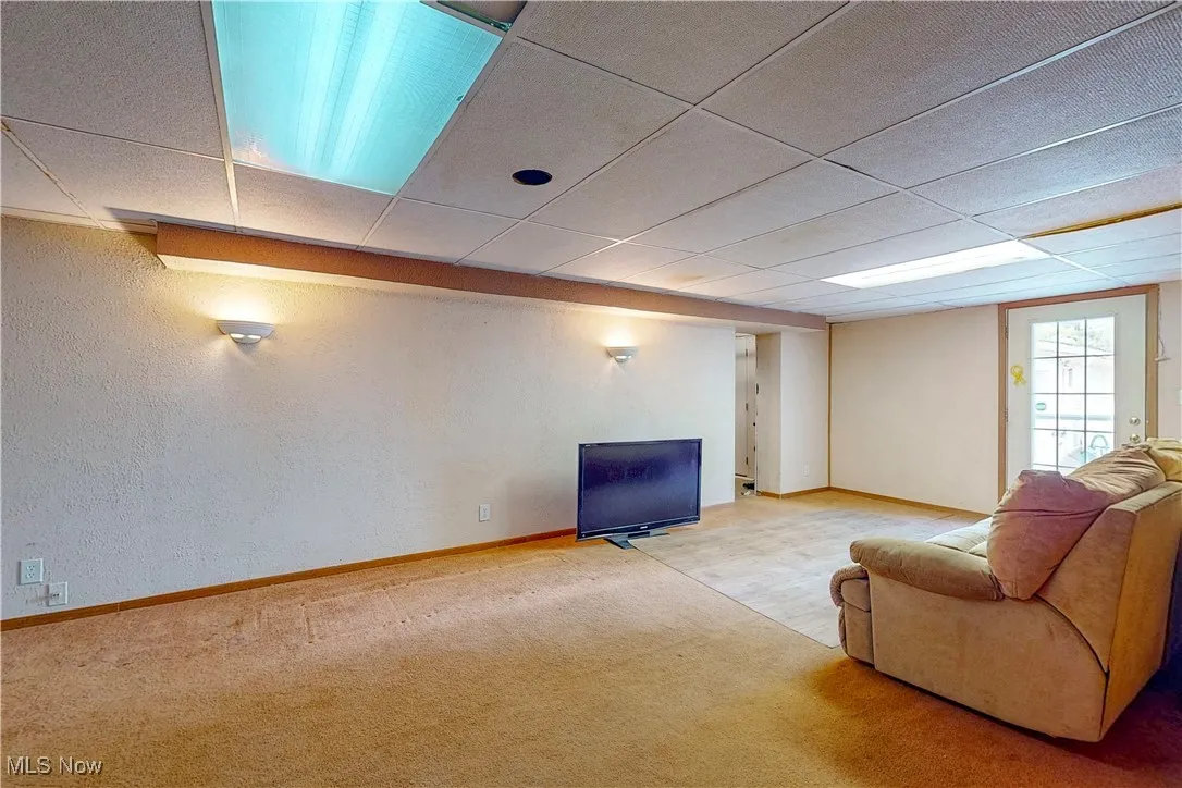 Living room with a drop ceiling, carpet, and a textured wall