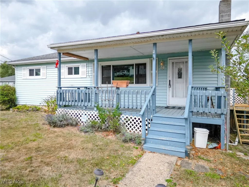 View of front of house with a porch, a chimney, and a front yard