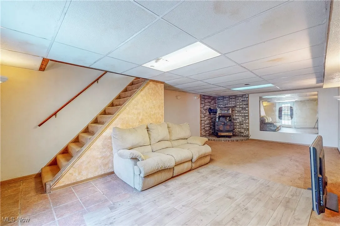 Living area with a wood stove, stairs, and a paneled ceiling