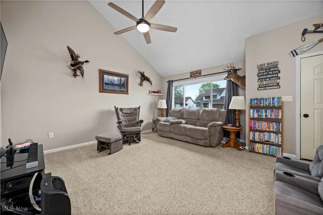 Living area featuring high vaulted ceiling, carpet floors, and ceiling fan