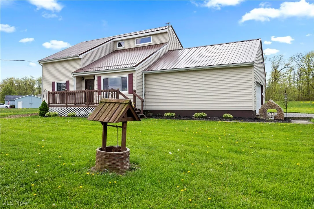 View of front facade featuring a deck, a front yard, and a metal roof